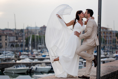 bride and groom playing with veil during honeymoon photo session at Garda Lake