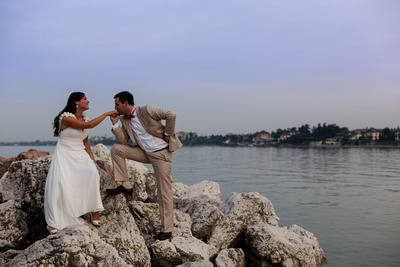 Russian couple sitting on stones next to Garda Lake in Desenzano during a honeymoon photo shooting