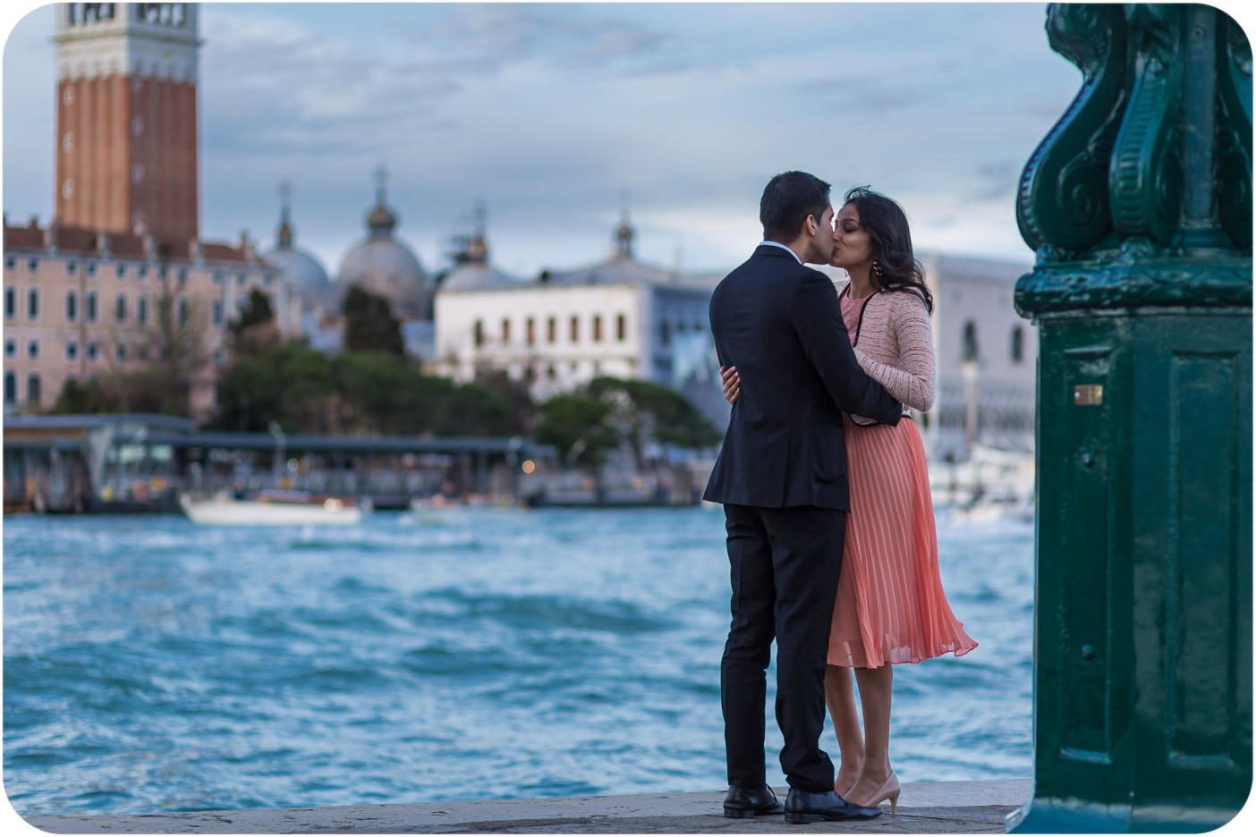 couple kiss in front of lagoon during engagement photo session in Venice